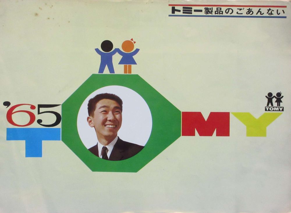 the cover of a 1965 Tomy catalogue, mostly blank white with a big '65 Tomy logo, there's a photo of a smiling man's head in the O, there's a little Japanese text top right