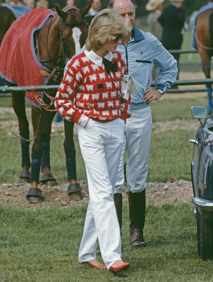 Princess Diana wearing a red sweater with a bunch of sheep on it, but on of them is a black sheep