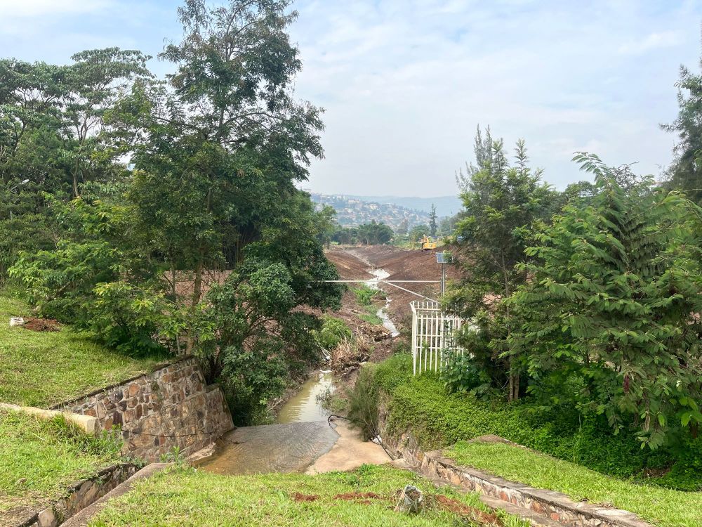 A water course with trees either side gives way to a view of groundwork in the distance, as a new wetland is being constructed in the city of Kigali. 