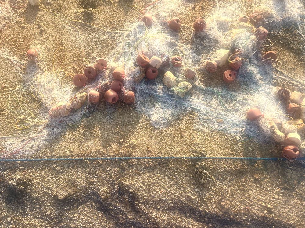 Fishing nets on a yellow, sand coloured surface, lit by an evening glow. 