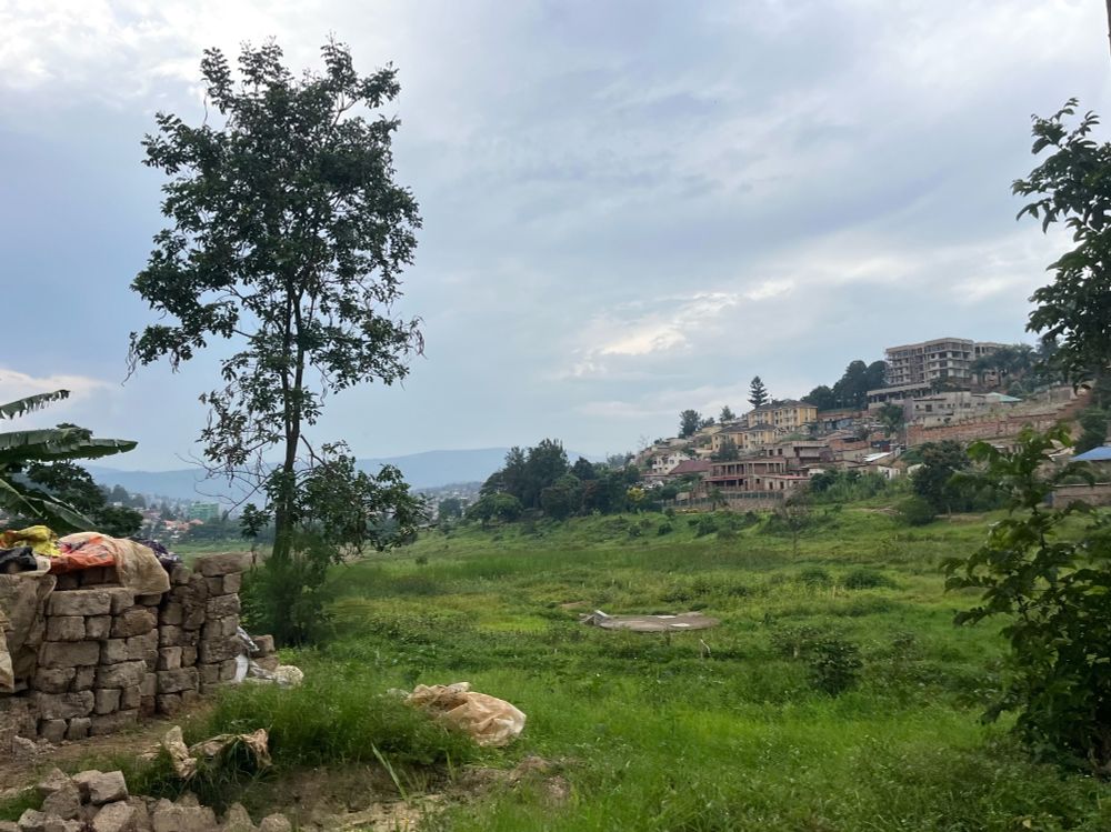 Green valley in Rwanda with housing across the entire hillside in the distance. 
