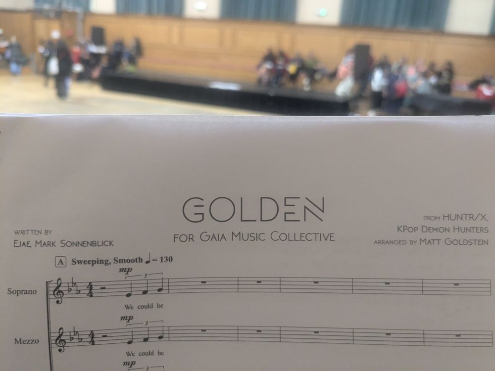 Picture of the top of a sheet music for Golden, written by Ejae, Mark Sonnenblick, from KPop demon hunters, arranged by Matt Goldstein for the Gaia Music Collective.

Above the sheet music, you can see a big room slowly getting filled.