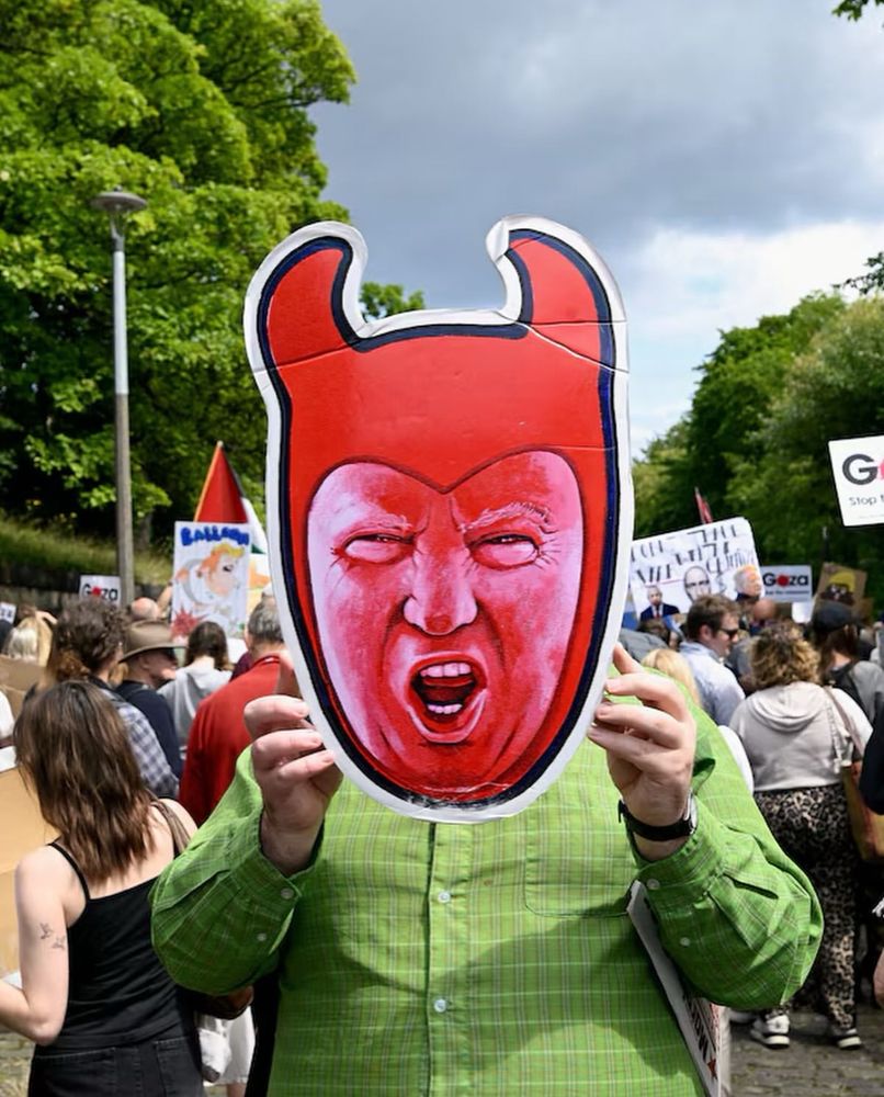 Photo of Scottish protester holding up a sign with Trump’s face as the devil