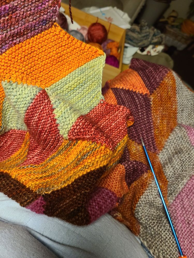 Many colours of garter stitched parallelograms. Green, oranges, pinks, browny rusts.