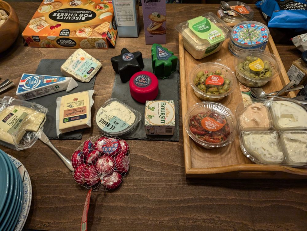 A table of various cheeses, dips and crackers. 