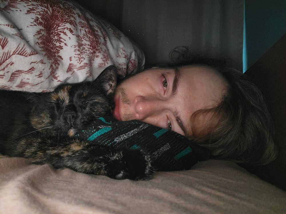 Me snuggling my cat in bed resisting waking up.