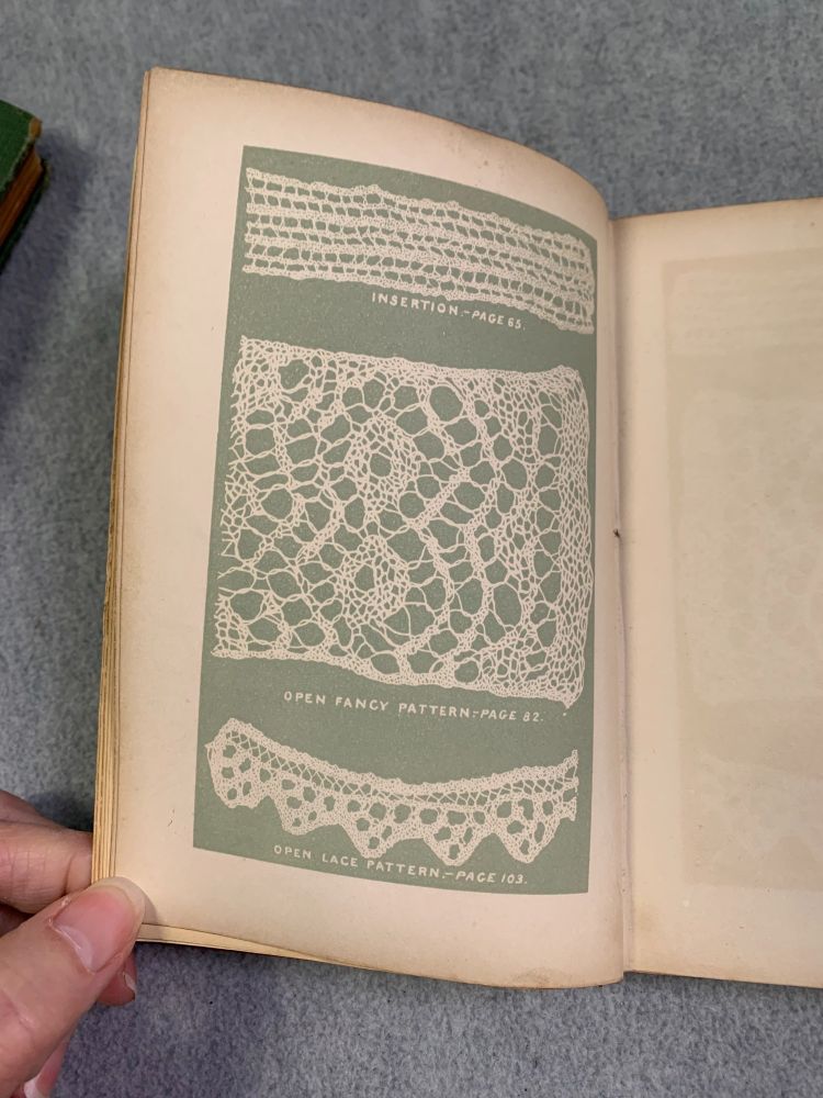 The book is opened to one of the early pages, where three of the lace patterns found in the book are pictured against a green background.