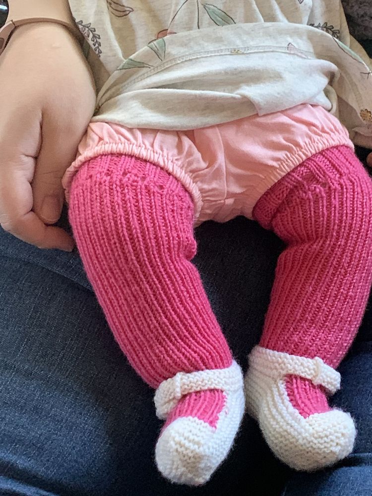 The stockings are modeled on a baby with chubby thighs, wearing a pair of pink bloomers under her knit dress.