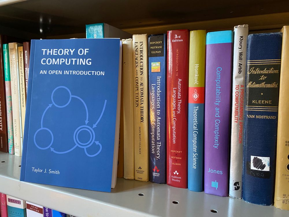 A photo of my open textbook, "Theory of Computing: An Open Introduction", on my bookshelf leaning up against some other classic theory texts.