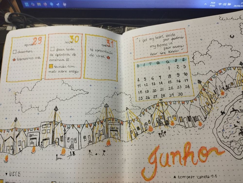 Mês de junho com tema São João: por duas páginas, desenho de uma rua de uma cidade pequena, com casinhas, luminárias, fogueiras e silhuetas de pessoas dançando, brincando, relaxando. Muito laranja e amarelo pra acentuar os desenhos. No resto da página, planejamento das semanas e o mês de Junho. 