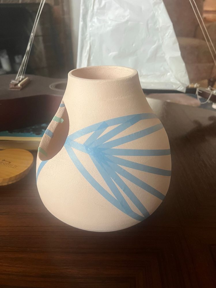 Side of a vase with a sort of feather or leaf looking pattern masking taped on the side