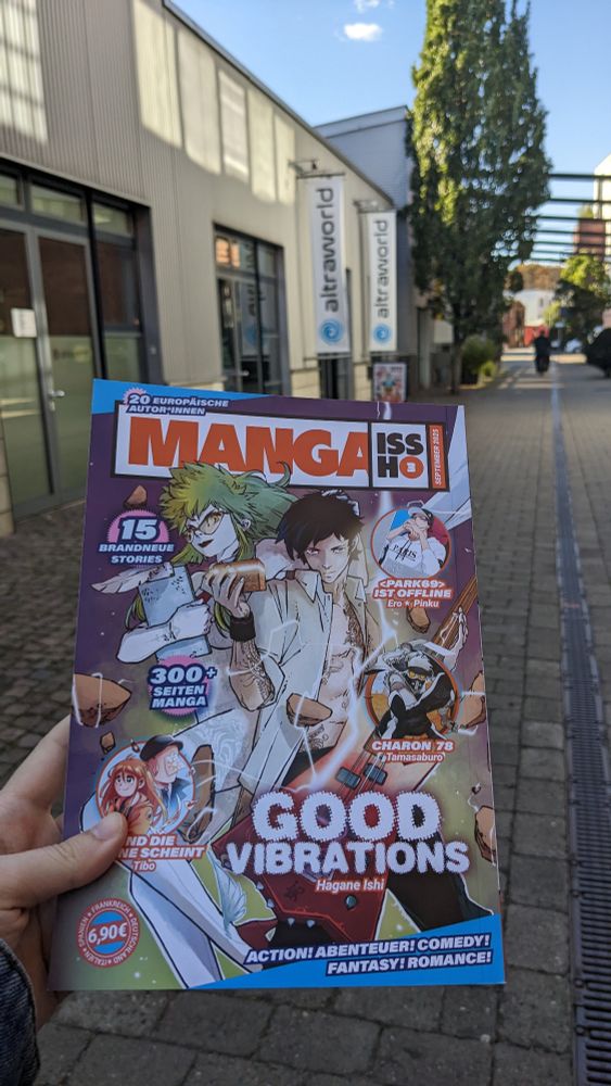 Photo of me holding volume 3 of manga issho Infront of altraverse shop