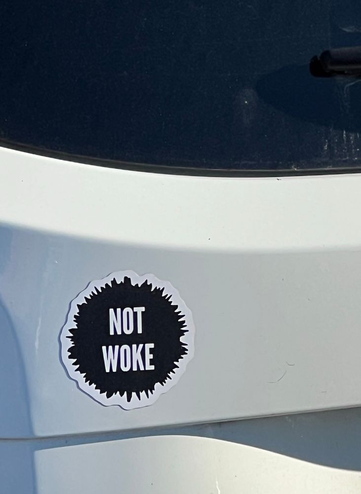 NOT WOKE sticker on a white car, just under the rear window