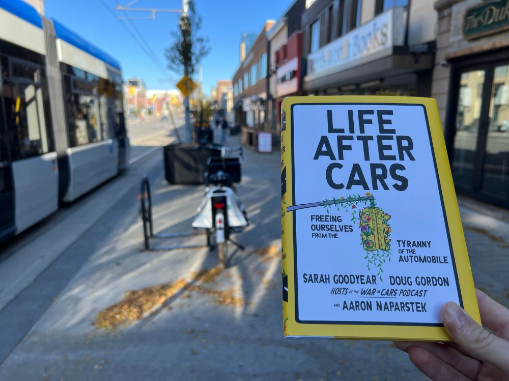 Life After Cars book with Waterloo city street background featuring Words Worth Books, a passing ION light rail train, and my Dutch bike 