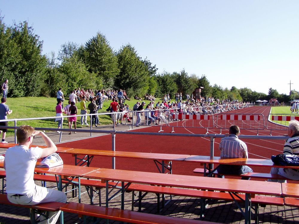 Ein Sportplatz mit Tartanbahn, Biertischen und provisorischen Absperrungen.