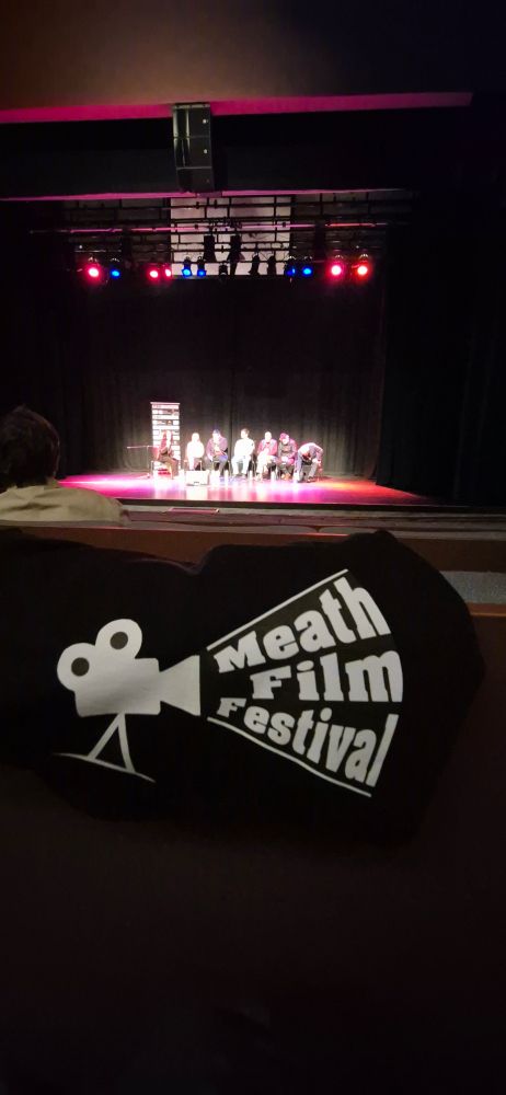 T-shirt with the Meath Film Festival logo draped over a seat while the Q&A begins on the stage beyond. 