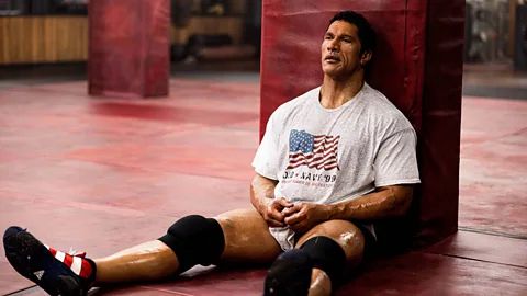 Promotional image of Johnson as Kerr sitting on the ground and wearing a shirt with an American flag