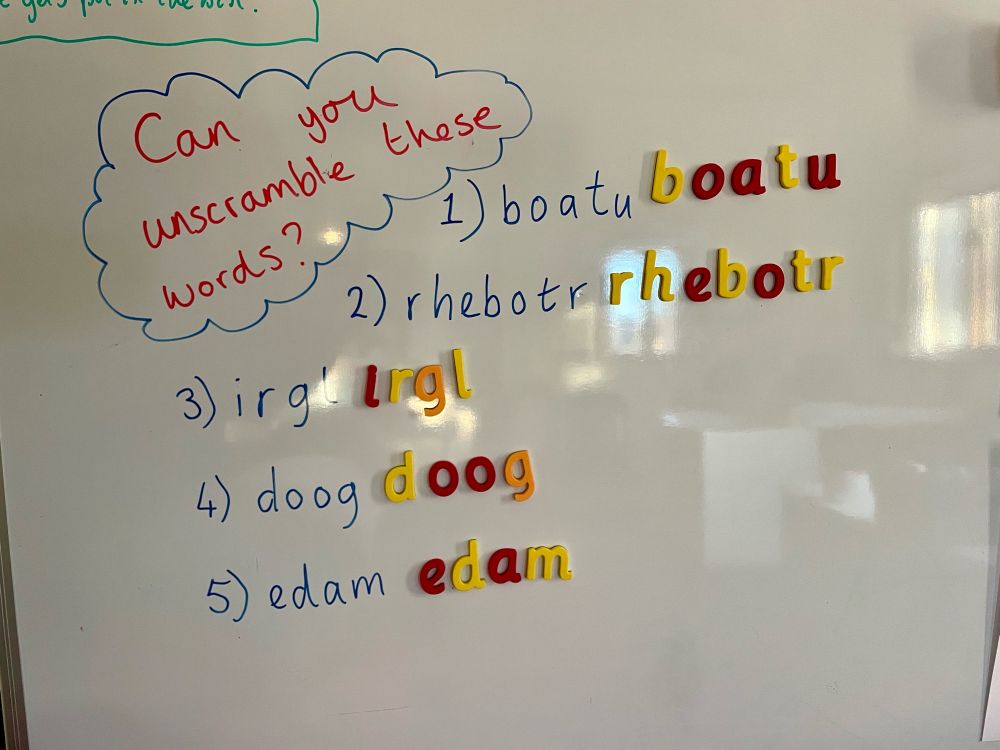 A whiteboard showing the question can you unscramble the words. Five words are written below, with the letters scrambled up, along with the corresponding magnetic letters. 