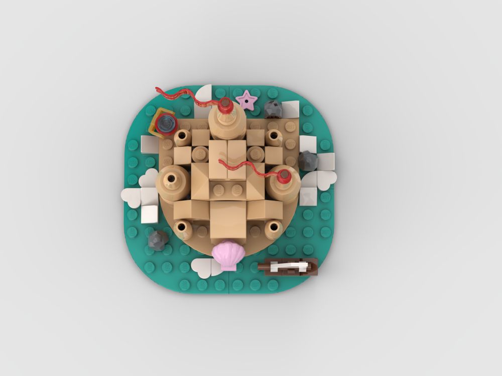 Top-down view of Lego sandcastle. Heart-shaped pieces are being used as white waves, there is a starfish and some rocks surrounding the castle.