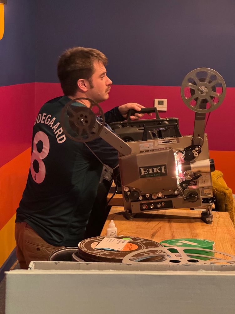 A man setting up a 16mm projector.