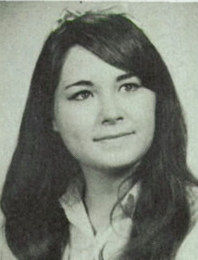 Black & white high school senior photo of Mom, a white woman with long dark hair smiling slightly.
