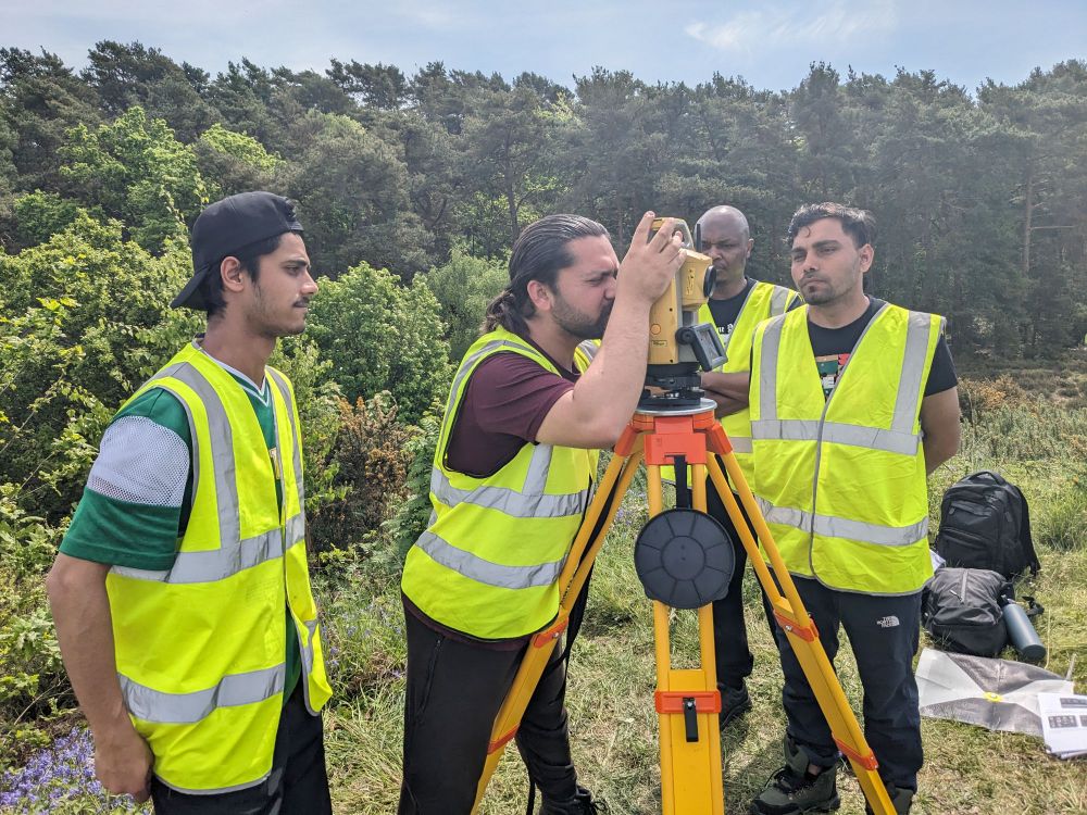 People in high-viz jackets using a total station surveying instrument 