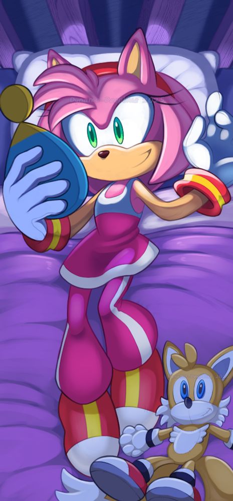 An illustration of Amy Rose wearing her outfit from Sonic Riders, by Dynamo-Deepblue. She is lying back on a bed with a purple blanket in a dark room, looking at the screen of a Chao-shaped smartphone, whose light is shining bright onto her face and pillow. A Tails plush is lying by her feet.