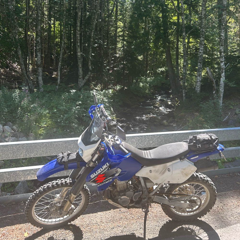 Dual sport motorcycle parked on a bridge on a forest service road.  