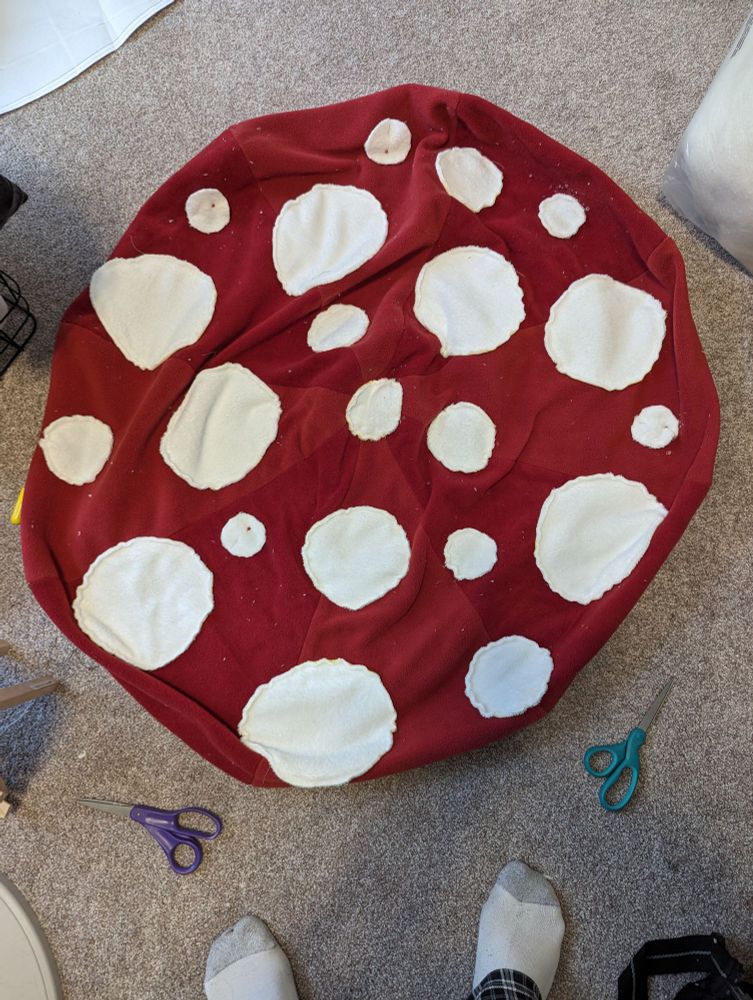 Flattened hat of the walking mushroom plush laid on a cluttered floor