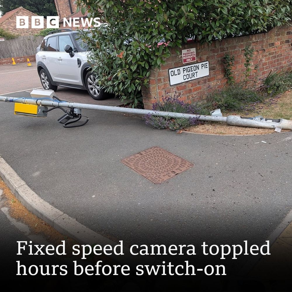 Photo accompanying a BBC news report about a toppled speed camera. Showing said toppled camera, attached to a pole lying on the ground, next to a wall with a sign that reads:"Old Pigeon Pie Court".