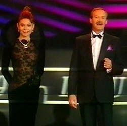 Presenters of Eurovision 1989, woman in a lacy number with a snake collar, and the man is a waiter