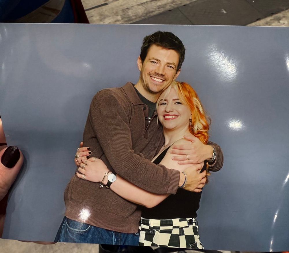 Fran being bugged by grant gustin. He’s wearing a cosy brown sweater. 