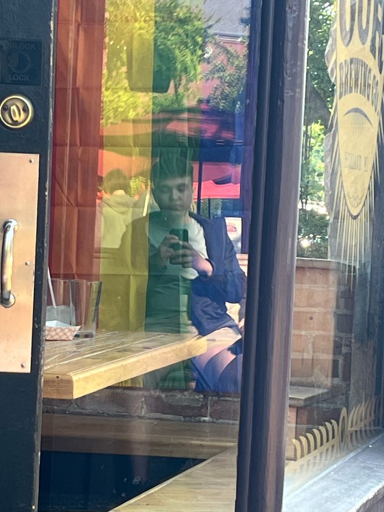 Selfie on the reflection of a window with a rainbow pride flag