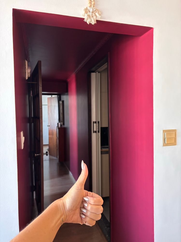 minha mão fazendo joinha de frente pra um corredor longo de cor vinho 