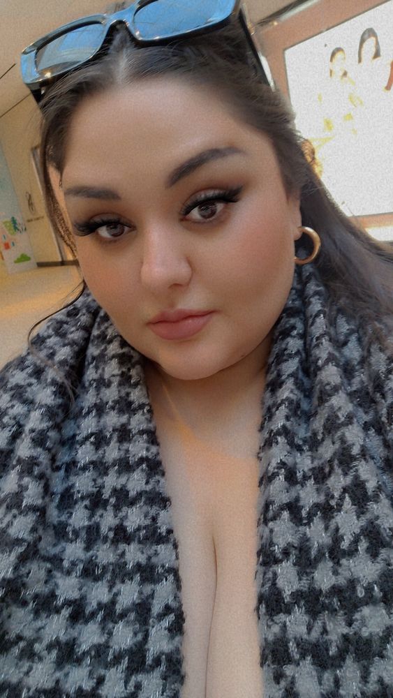 Destiny is wearing hoop earring, sunglasses and a scarf. She is taking a Selfie in the mall