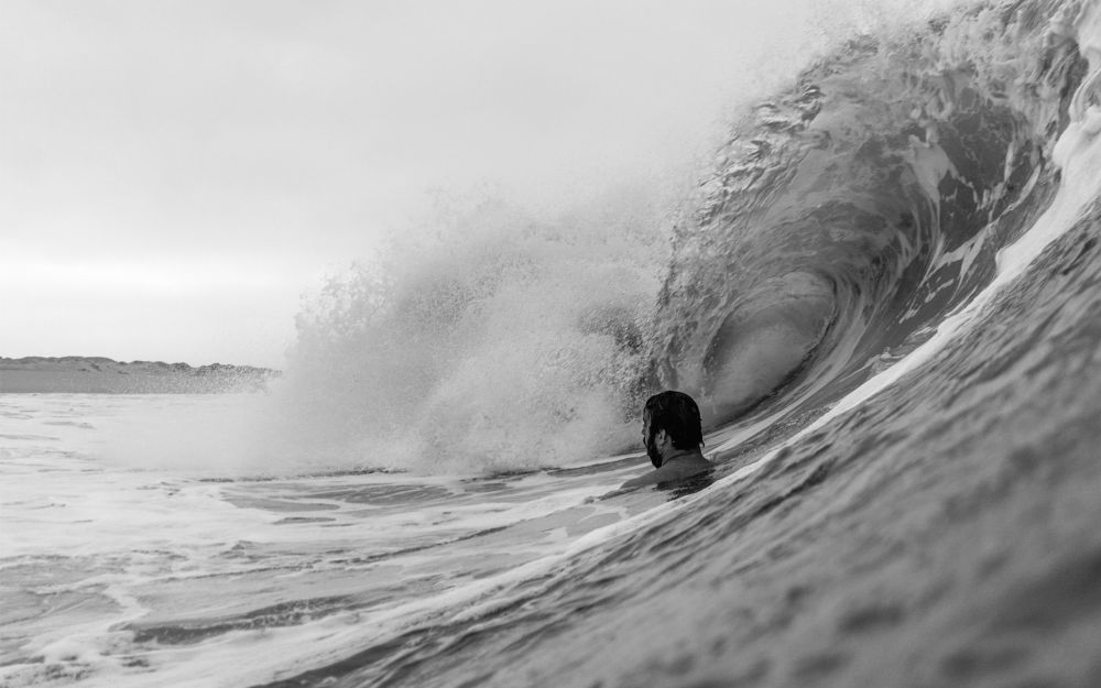 Landscape view bodysurfer looking towards the beach as a barreling wave is about to pass overhead