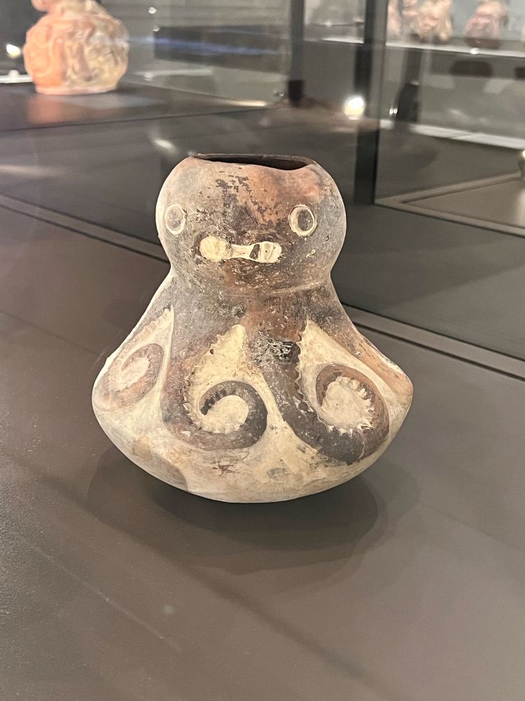 a little ceramic octopus vase or jar from far in the past with a very goofy grin