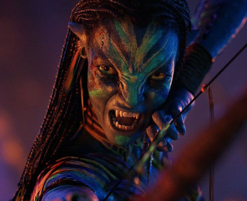 Neytiri snarling and using her bow. The ground is a blurred but has a strong purple hue.