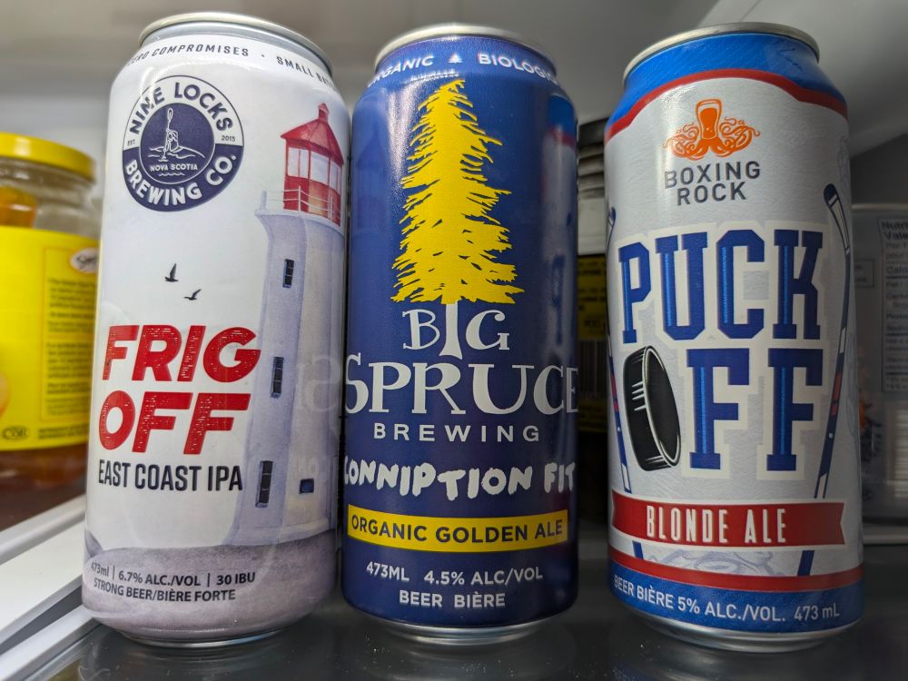 Three cans of local Nova Scotian beer, named 'Frig Off' East Coast IPA,  'Conniption Fit's Organic Golden Ale and 'Puck Off' Blonde Ale.