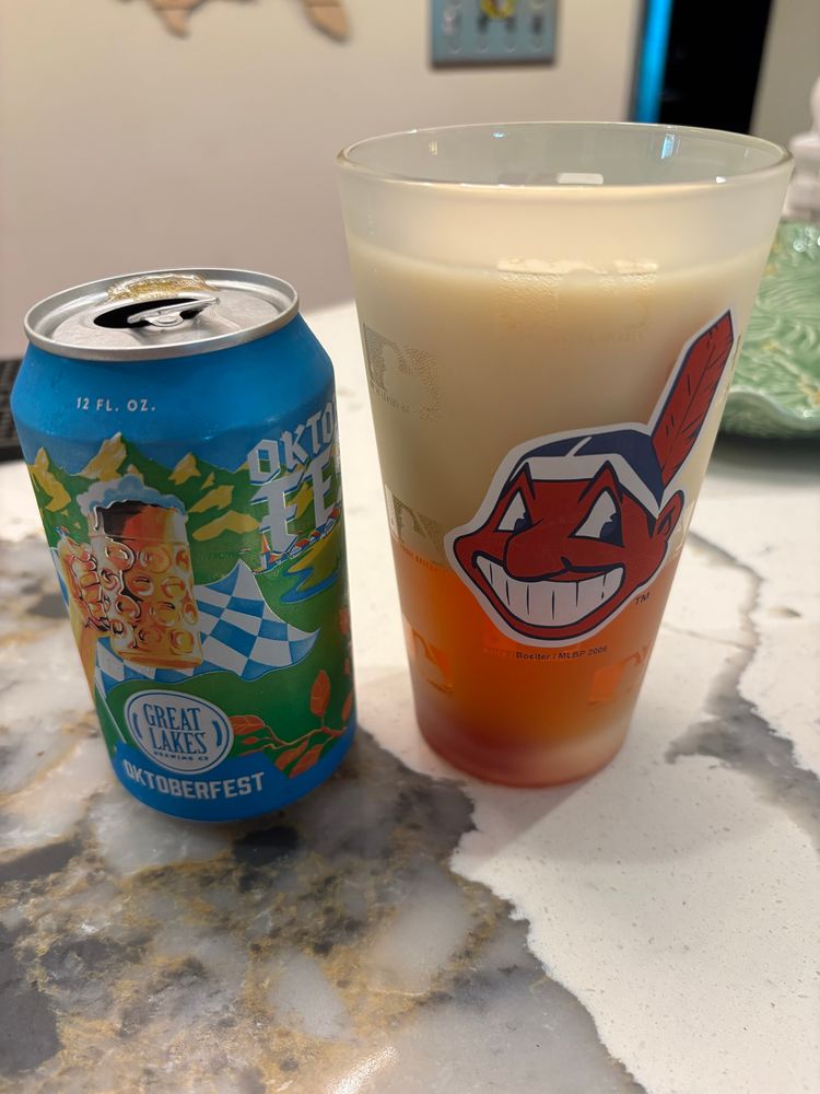 Great Lakes Oktoberfest beer can beside a Cleveland Indians pint class filled with beer and a big head of foam. 