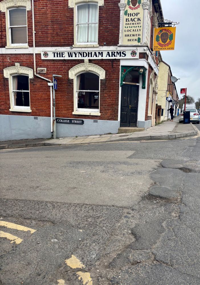 Pub called the Wyndham Arms with potholes in the road outside 