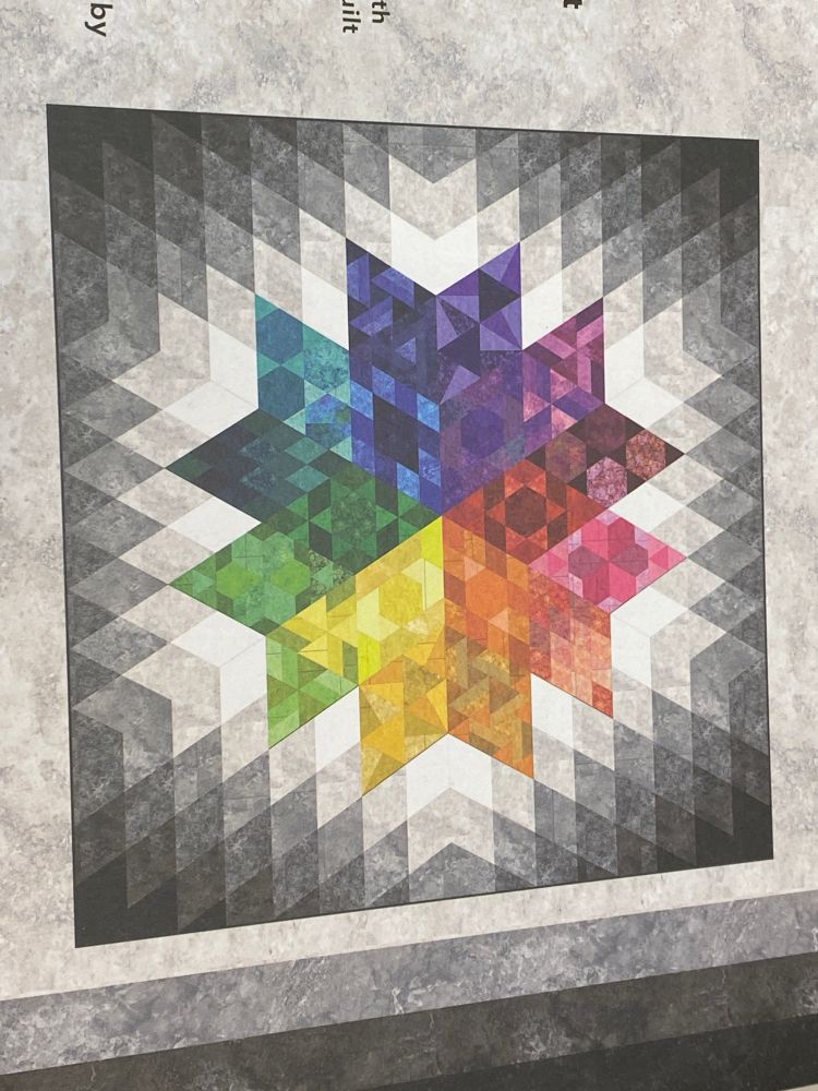 Rainbow colored Diamond pattern in the center with white and greys radiating out to the dark edges of the quilt top.