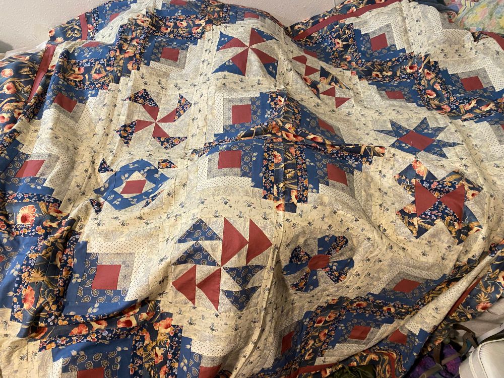 Log cabin blocks enclose a variety of other pieced blocks. The workmanship is exquisite, but the country blue and mauve tones are quite dated.