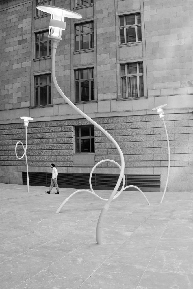 A forecourt of an office building in Frankfurt with curved street lamps. An installation by Danish artist Jeppe Hein.