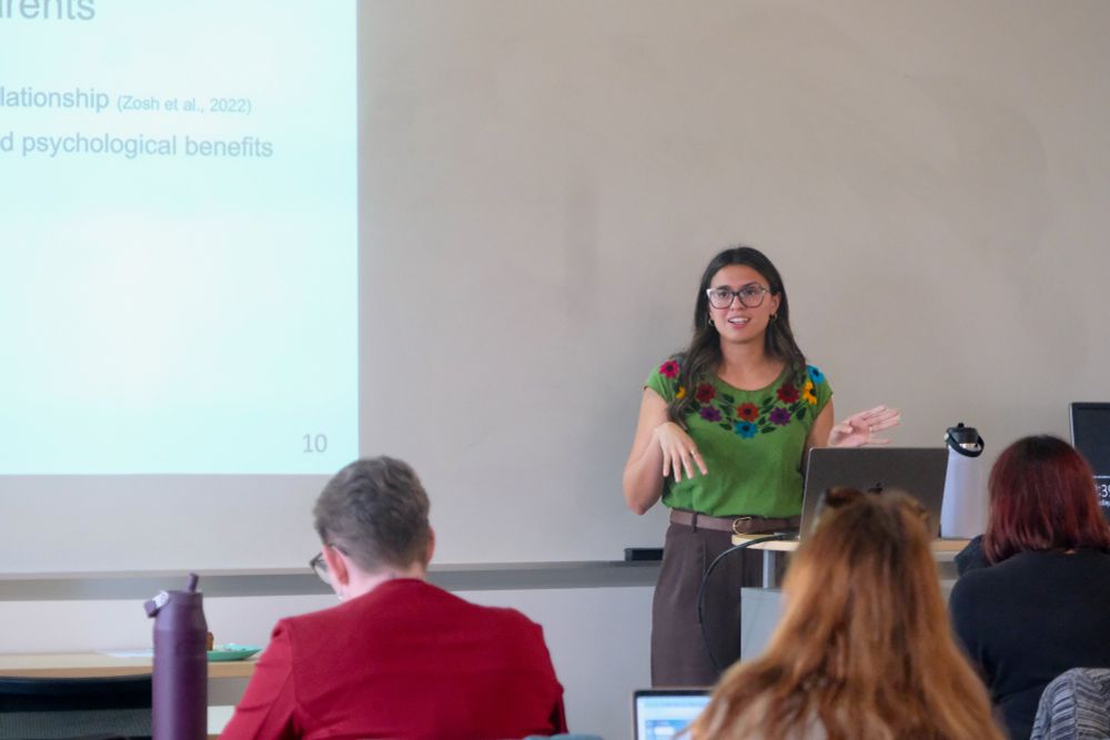 Alexus Ramirez presents while standing at a computer, in front of a whiteboard with a projection
