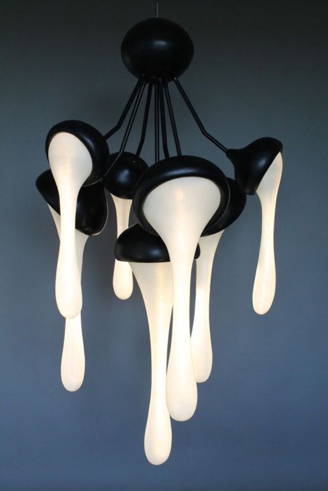 A black lamp with seven separate bulbs against a dark bluish gray background.  The bulbs are covered by what designed to appear to be a dripping, oozy substance, more than vaguely resembling globs of cum