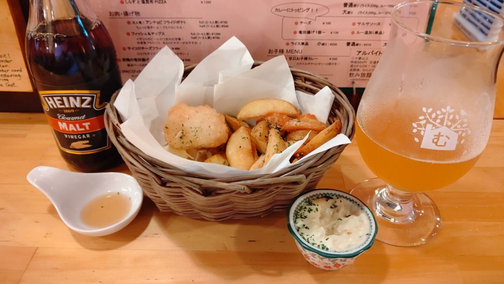 カウンターを背景に、モルトビネガー、バスケットに盛られたフィッシュアンドチップス、小皿に入ったタルタルソース、グラスに注がれたセゾンビール「西風」