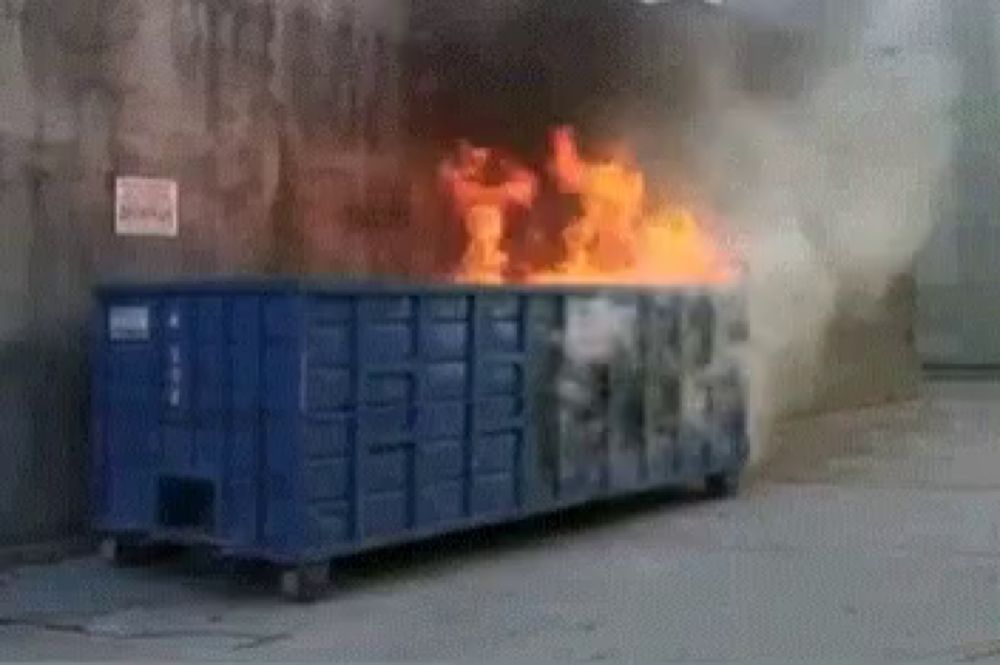 a dumpster is on fire and smoke is coming out of it .