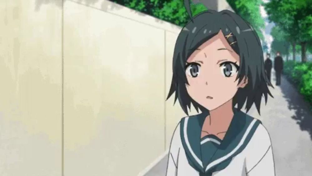 a girl in a school uniform is standing on a sidewalk looking at something .