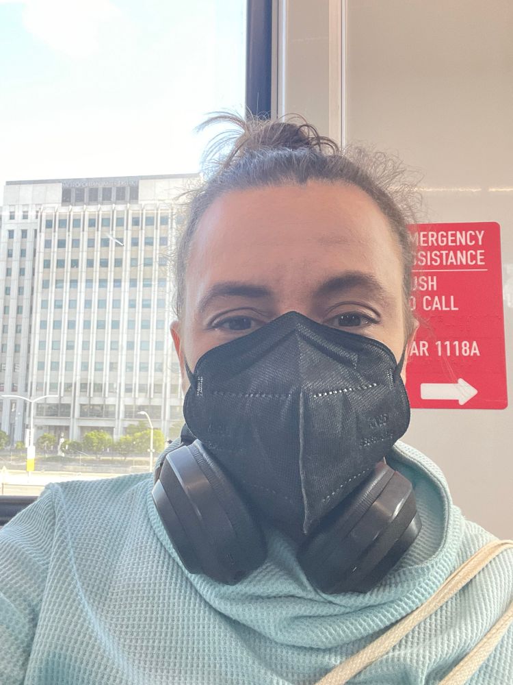 Brown-haired person in a mask on a train 